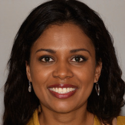 Joyful black young-adult female with long  brown hair and brown eyes