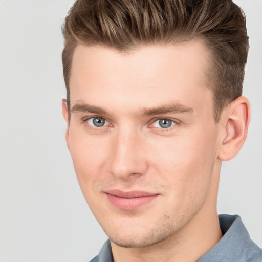 Joyful white young-adult male with short  brown hair and grey eyes