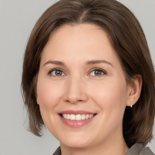 Joyful white adult female with medium  brown hair and grey eyes