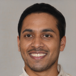 Joyful latino young-adult male with short  black hair and brown eyes