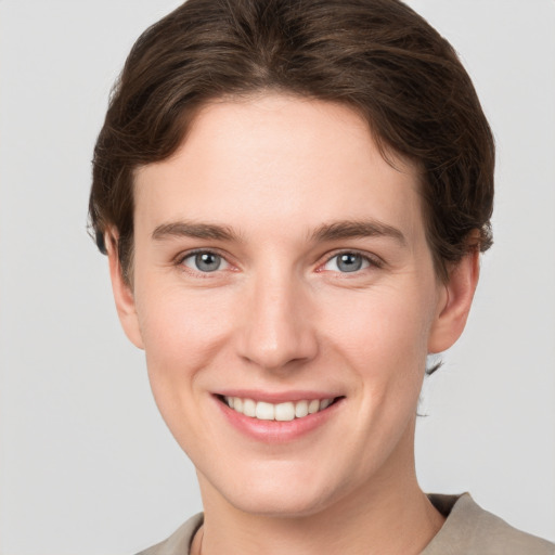 Joyful white young-adult female with short  brown hair and grey eyes