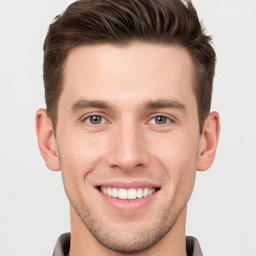 Joyful white young-adult male with short  brown hair and grey eyes