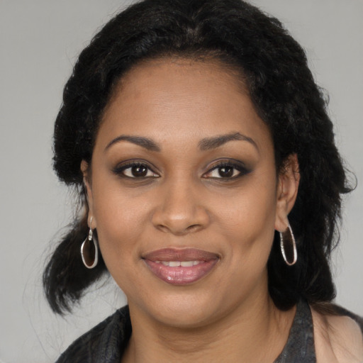 Joyful black young-adult female with long  black hair and brown eyes