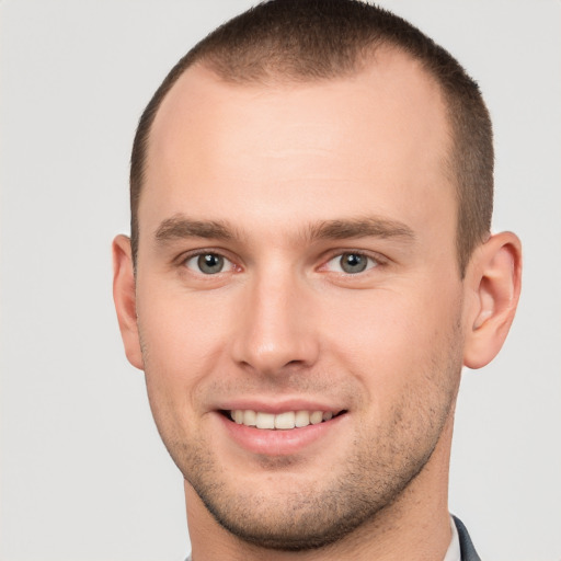 Joyful white young-adult male with short  brown hair and grey eyes