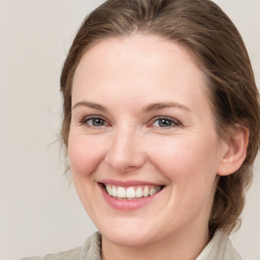 Joyful white young-adult female with medium  brown hair and grey eyes