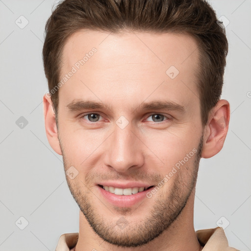 Joyful white young-adult male with short  brown hair and grey eyes