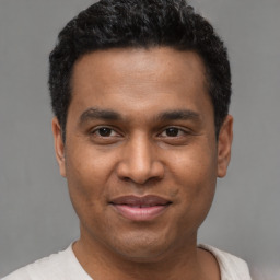 Joyful latino young-adult male with short  black hair and brown eyes