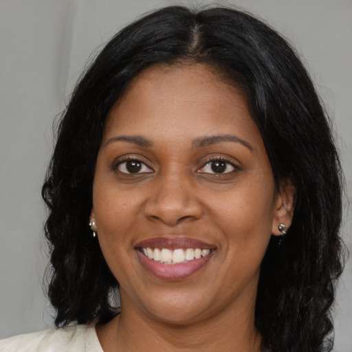 Joyful black young-adult female with long  brown hair and brown eyes