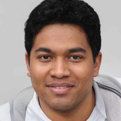 Joyful latino young-adult male with short  black hair and brown eyes