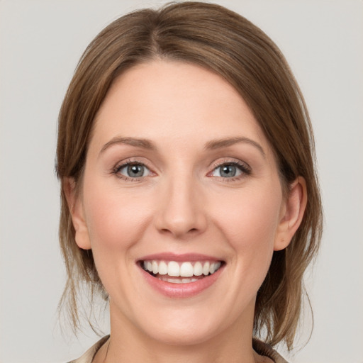 Joyful white young-adult female with medium  brown hair and grey eyes