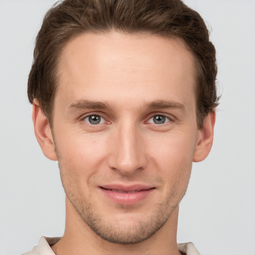 Joyful white young-adult male with short  brown hair and grey eyes