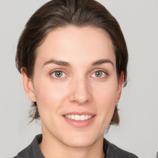 Joyful white young-adult female with medium  brown hair and grey eyes