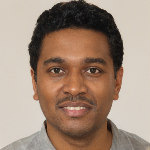 Joyful black young-adult male with short  black hair and brown eyes