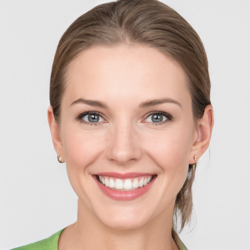 Joyful white young-adult female with medium  brown hair and grey eyes