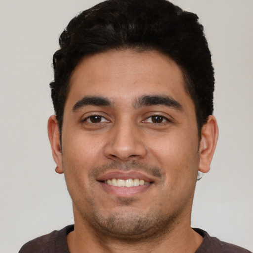 Joyful latino young-adult male with short  black hair and brown eyes