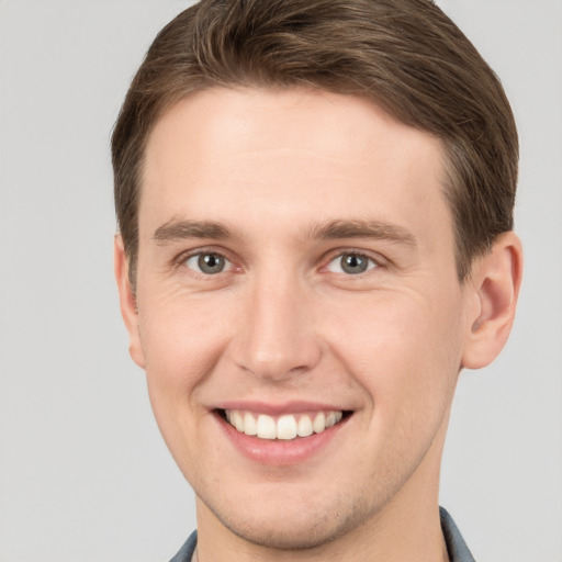 Joyful white young-adult male with short  brown hair and grey eyes