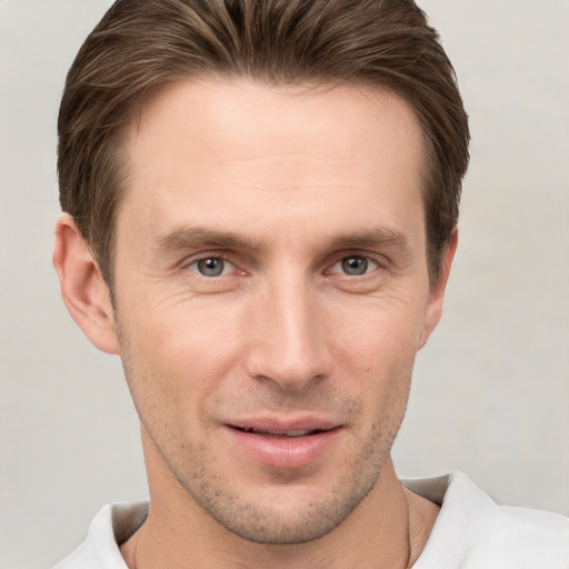 Joyful white young-adult male with short  brown hair and grey eyes