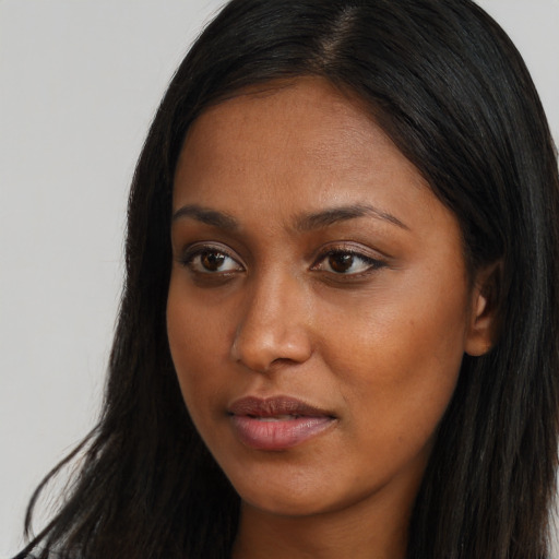 Joyful black young-adult female with long  brown hair and brown eyes