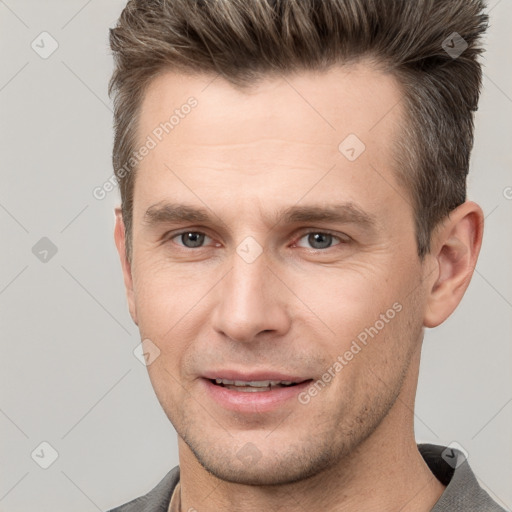 Joyful white young-adult male with short  brown hair and grey eyes