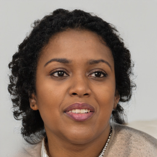 Joyful black young-adult female with long  brown hair and brown eyes
