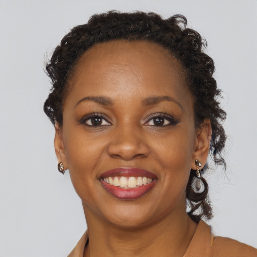 Joyful black young-adult female with long  brown hair and brown eyes