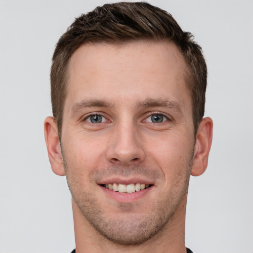 Joyful white young-adult male with short  brown hair and grey eyes