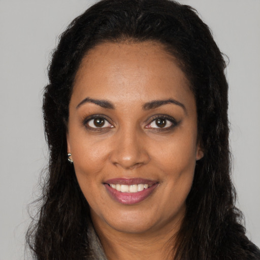 Joyful black young-adult female with long  brown hair and brown eyes