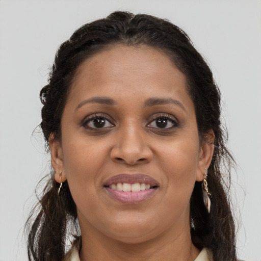 Joyful black young-adult female with long  brown hair and brown eyes