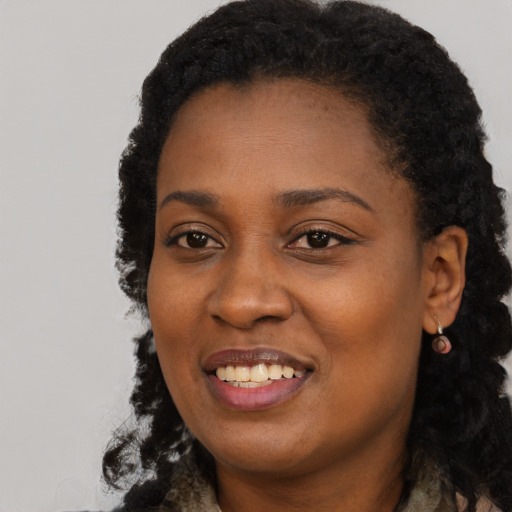 Joyful black young-adult female with long  black hair and brown eyes