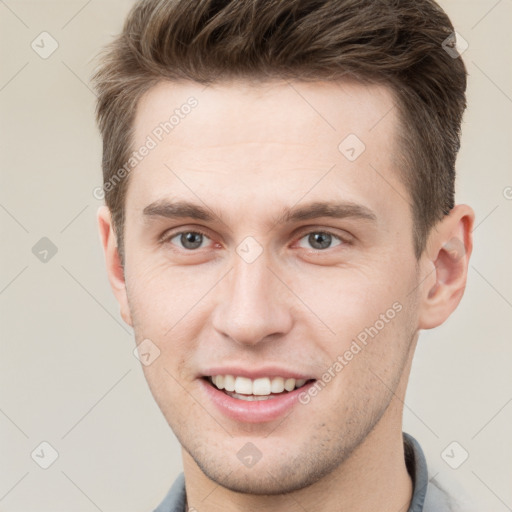 Joyful white young-adult male with short  brown hair and grey eyes