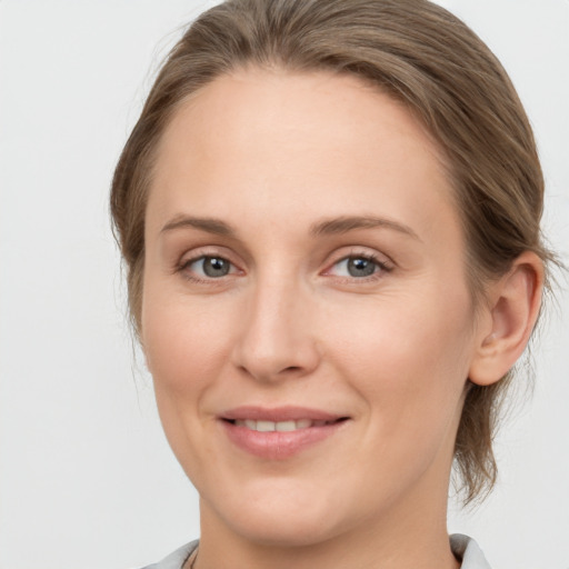 Joyful white young-adult female with medium  brown hair and grey eyes