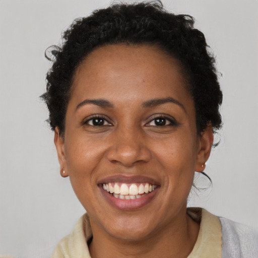 Joyful black young-adult female with short  black hair and brown eyes