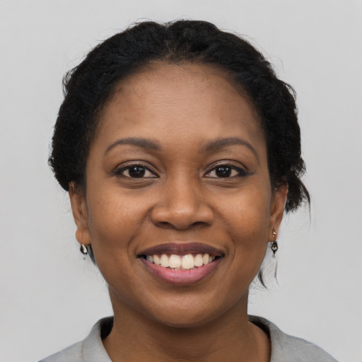 Joyful black young-adult female with short  black hair and brown eyes