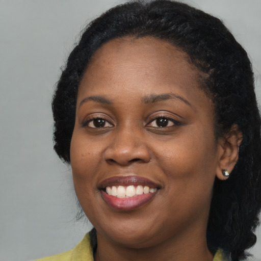 Joyful black young-adult female with long  brown hair and brown eyes