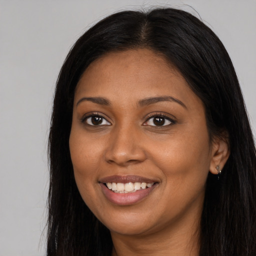 Joyful black young-adult female with long  brown hair and brown eyes
