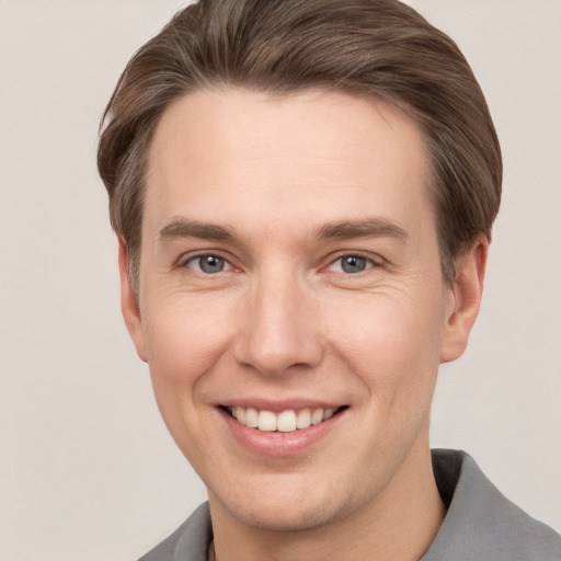 Joyful white young-adult male with short  brown hair and grey eyes