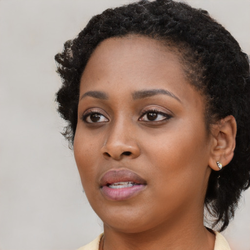 Joyful black young-adult female with long  black hair and brown eyes