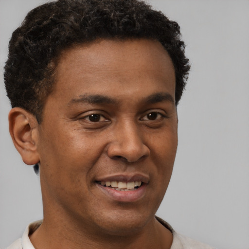 Joyful black young-adult male with short  brown hair and brown eyes