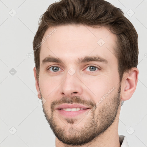 Joyful white young-adult male with short  brown hair and grey eyes