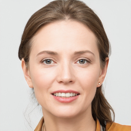 Joyful white young-adult female with medium  brown hair and grey eyes