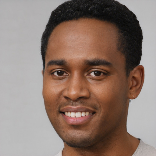 Joyful black young-adult male with short  black hair and brown eyes