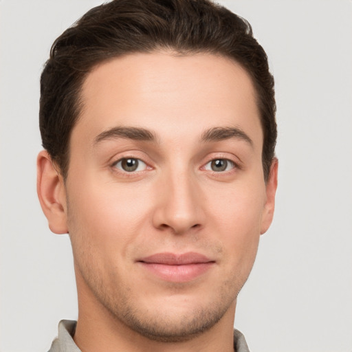 Joyful white young-adult male with short  brown hair and grey eyes