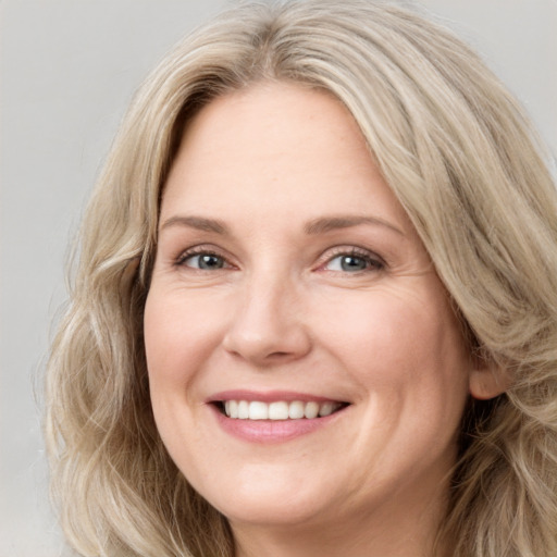 Joyful white adult female with long  brown hair and blue eyes