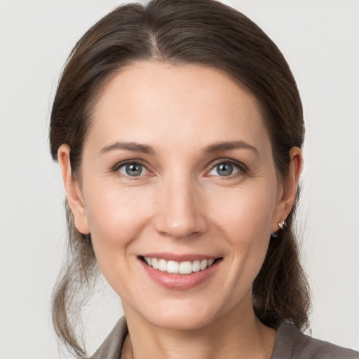 Joyful white young-adult female with medium  brown hair and grey eyes