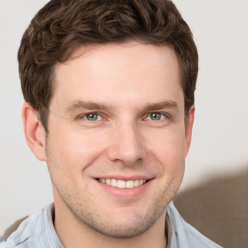 Joyful white young-adult male with short  brown hair and grey eyes