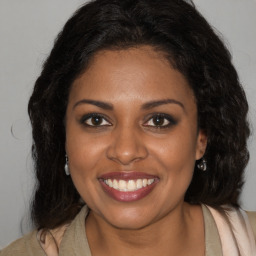 Joyful black young-adult female with long  brown hair and brown eyes