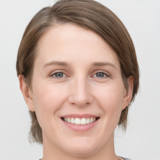 Joyful white young-adult female with medium  brown hair and grey eyes