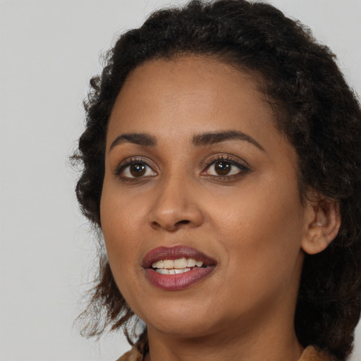 Joyful black young-adult female with long  brown hair and brown eyes