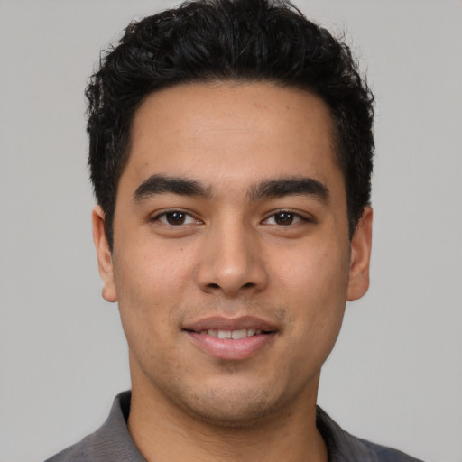 Joyful latino young-adult male with short  black hair and brown eyes
