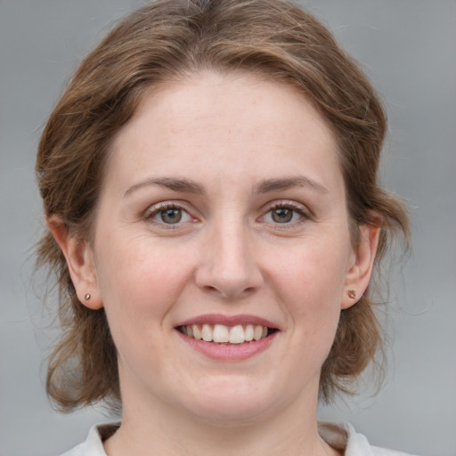 Joyful white young-adult female with medium  brown hair and grey eyes